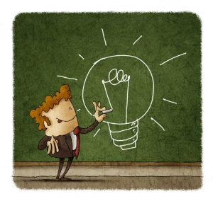 Businessman drawing a light bulb on a green chalkboard